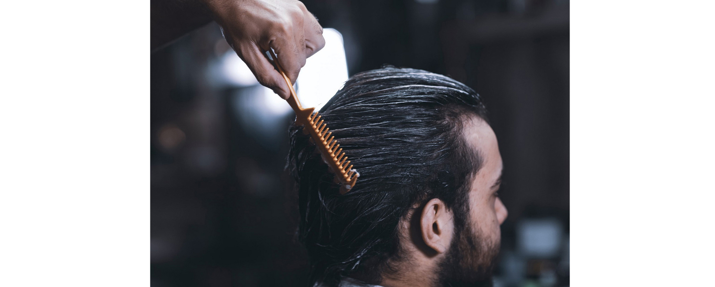 Person combing through wet, treated hair with a fine-toothed comb during a hair care routine.